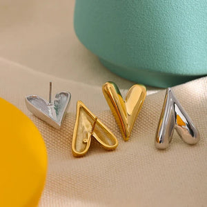 Gold and silver letter 'V' charms on a beige surface with a teal container in the background.