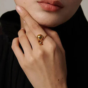 Woman wearing a modern 18K gold-plated silver ring with two spherical accents.