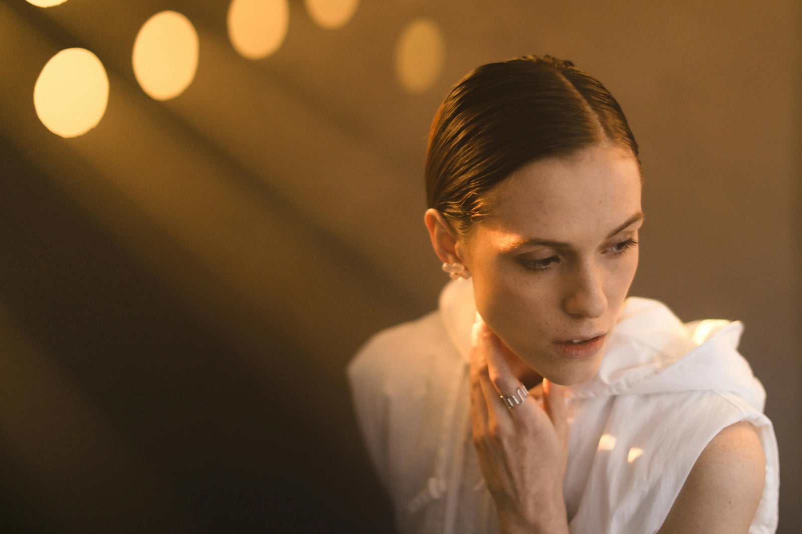 Close-up of a model showcasing sterling silver rings, captured in dramatic golden light with a minimalist, quiet luxury aesthetic.