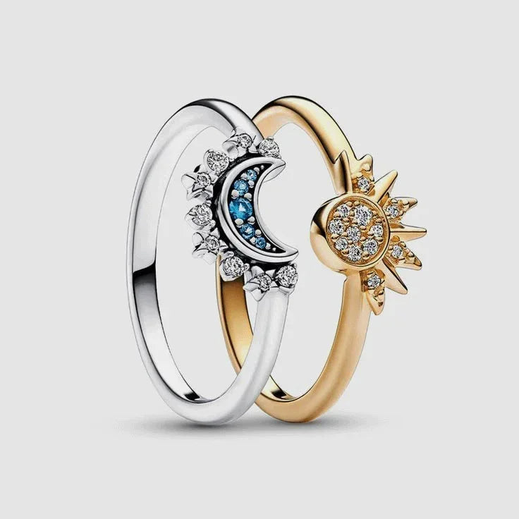 Two rings, one silver with a moon design and one gold with a sun design, on a light gray background.
