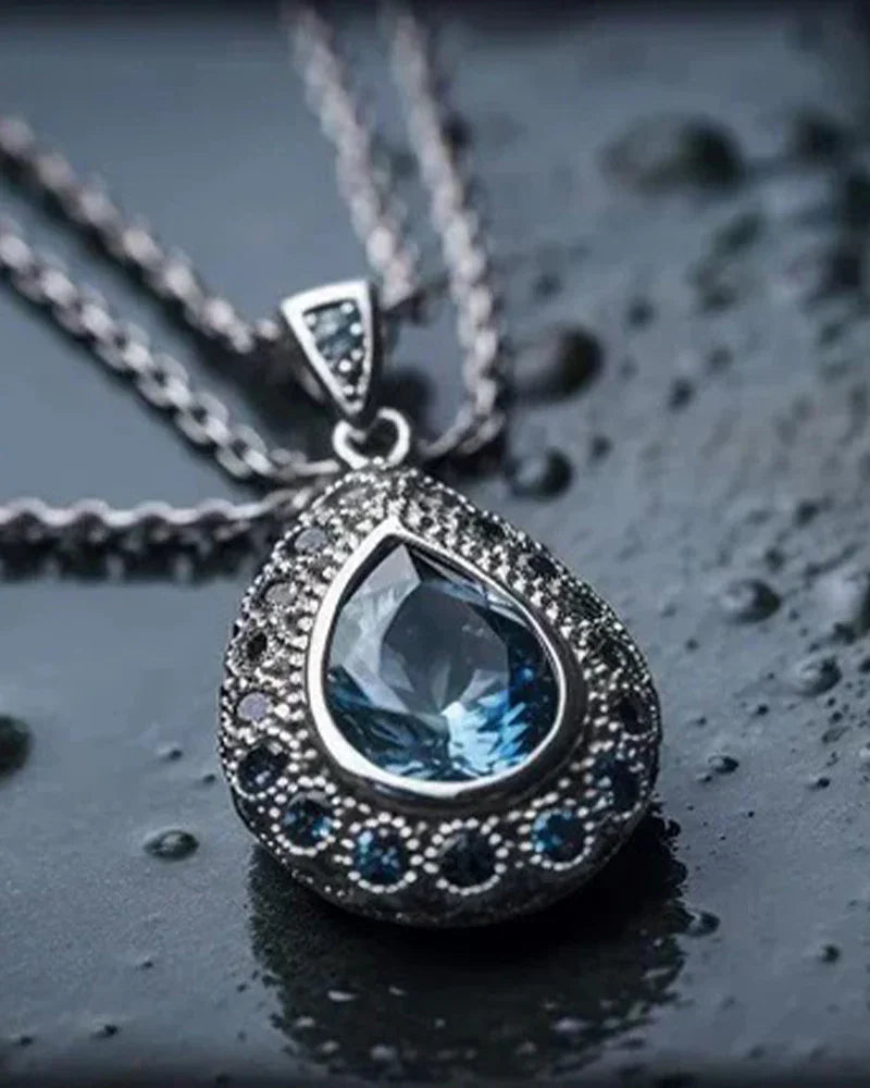Handcrafted sterling silver teardrop necklace featuring a brilliant blue gemstone, styled for elegant gifting.