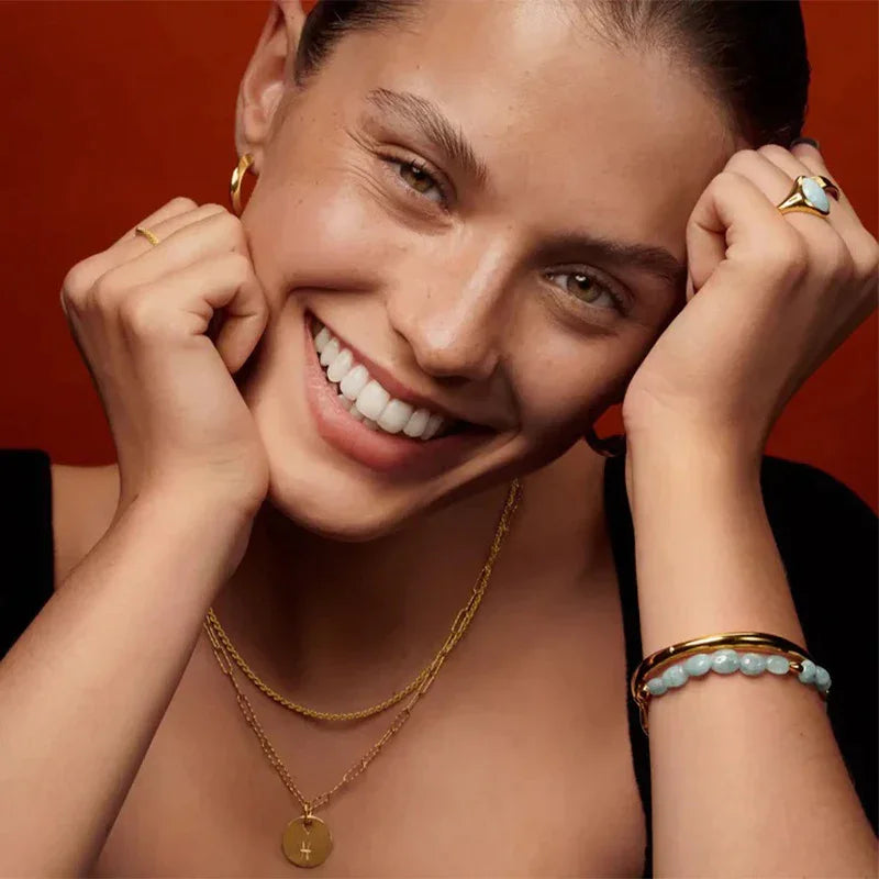 Portrait of a woman wearing gold-plated necklaces and bracelets by TM & Co. Jewels