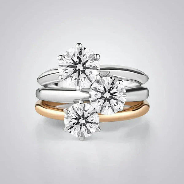 A elegant stack of solitaire diamond rings from the TM & Co. Jewels collection, featuring a mix of precious metal bands.